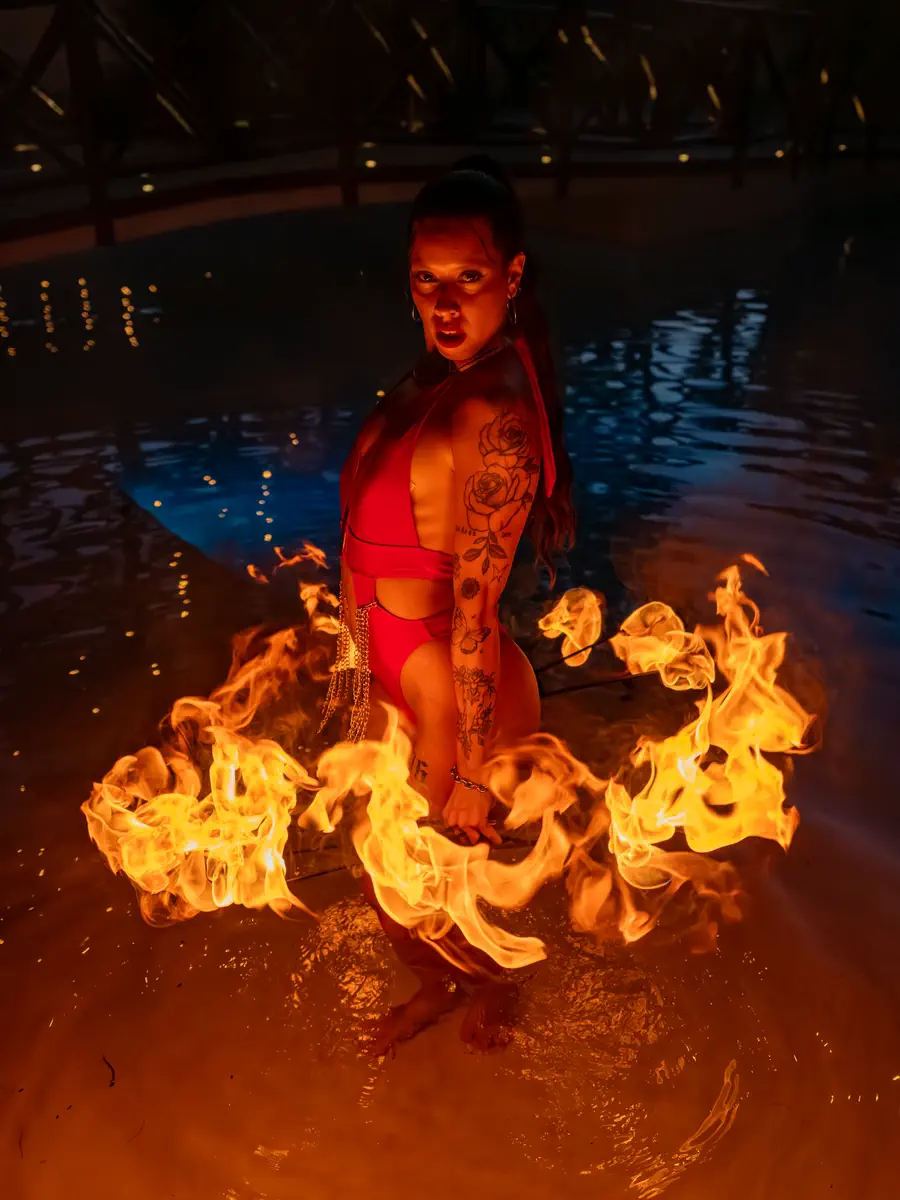 Performer in red inside the pool surrounded by a ring of flames