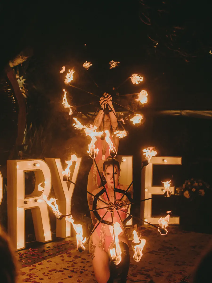 Performer kneeling in front of giant letters lit in flames