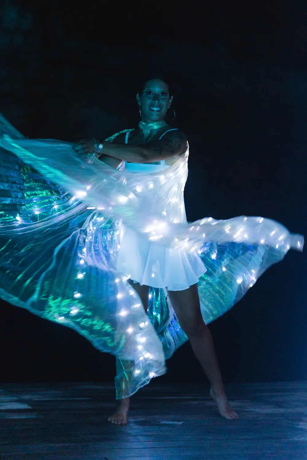 Dancer with LED wing lights spinning on a dark stage